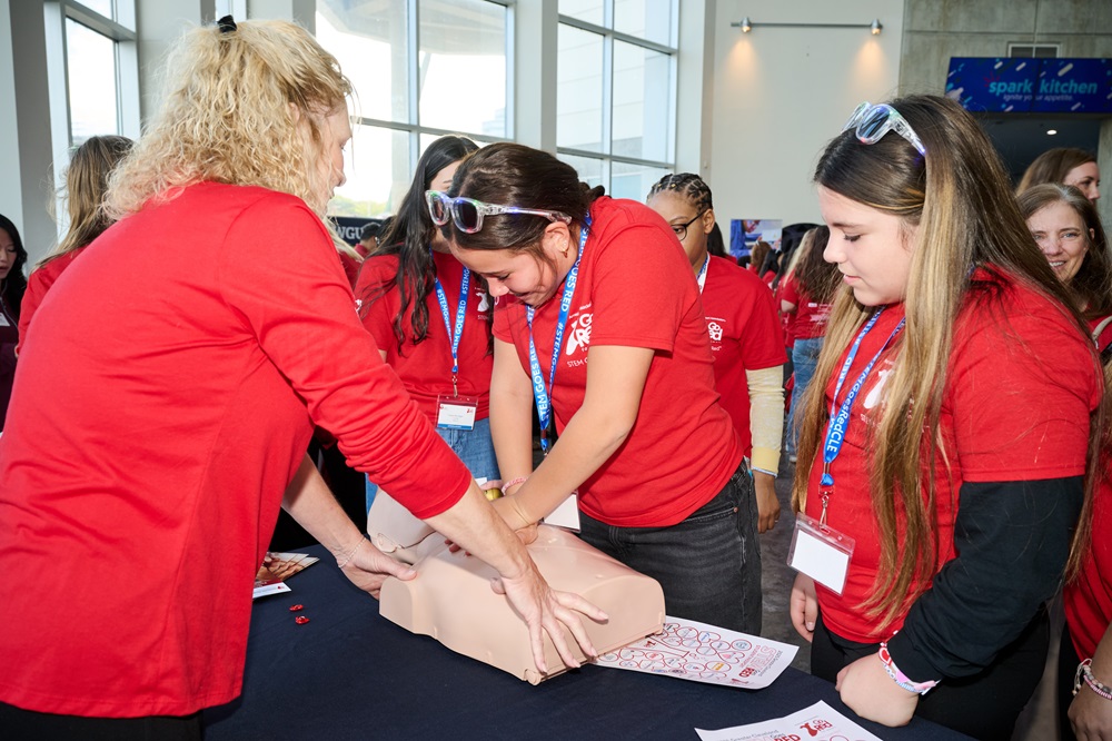 Woman showing two girls how to do hands-only CPR.